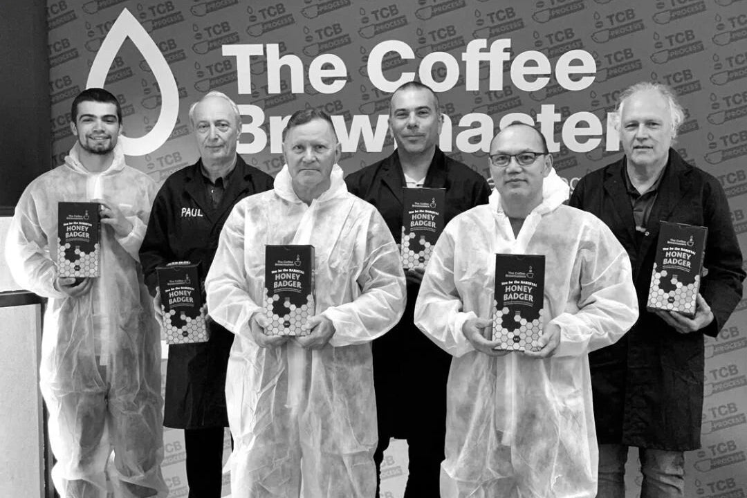 The Coffee Brewmasters team in lab coats holding the range